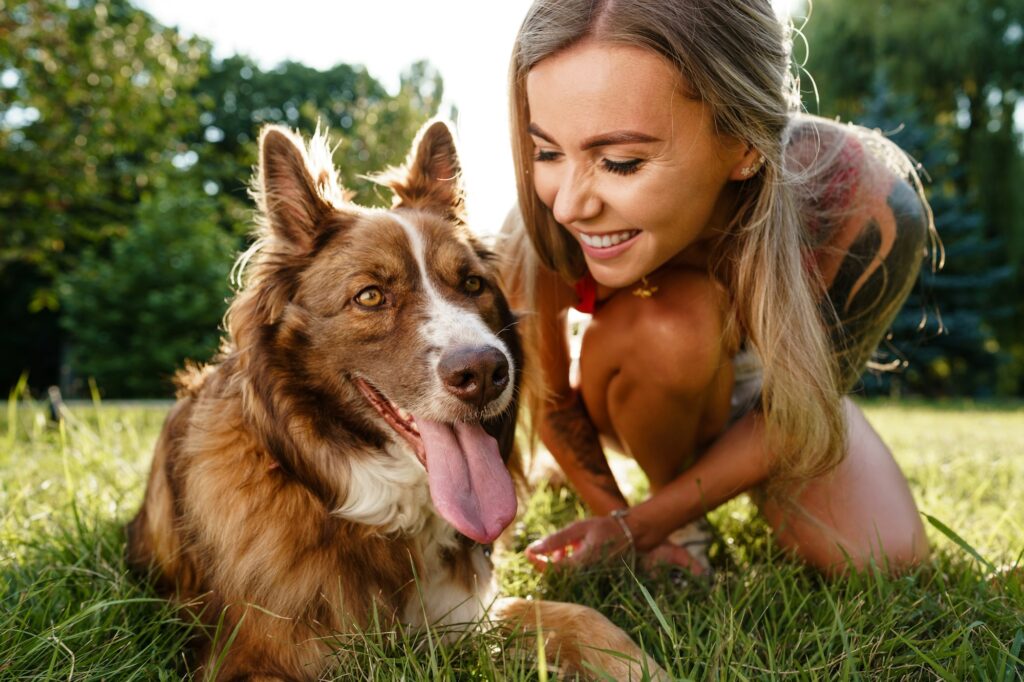 Young woman with her dog sitting on grass