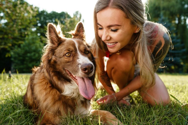 Young woman with her dog sitting on grass