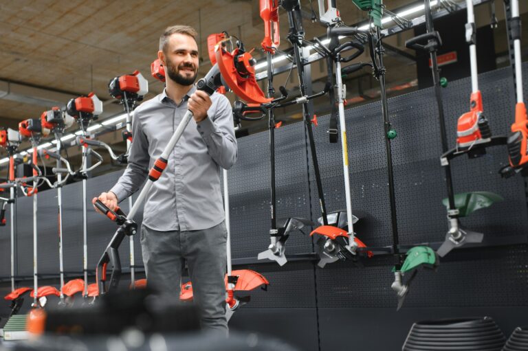 happy customer with electric lawn trimmer in hands at garden equipment store