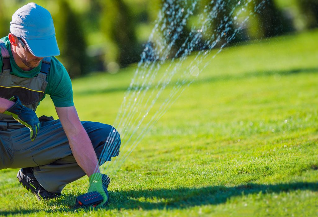 A professional is adjusting a lawn sprinkler position to ensure proper water distribution.