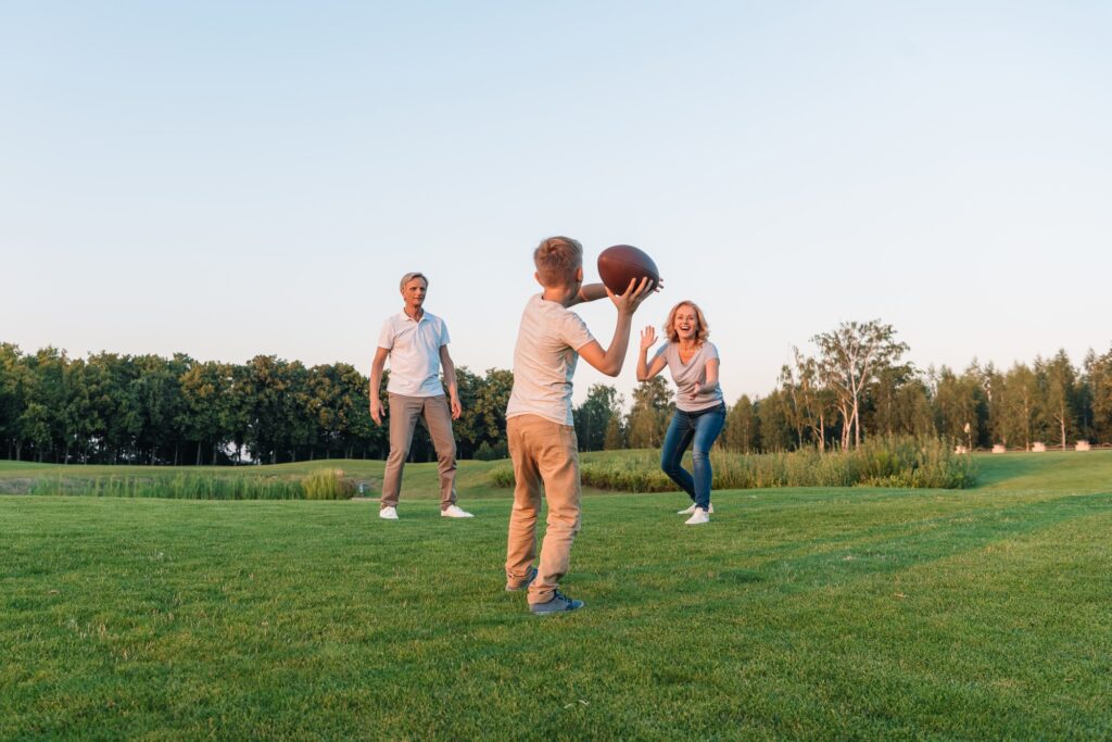 little boy going to throw football while playing american football with grandparents on green lawn for 4th of July little boy going to throw football while playing american football with grandparents on green lawn for 4th of July